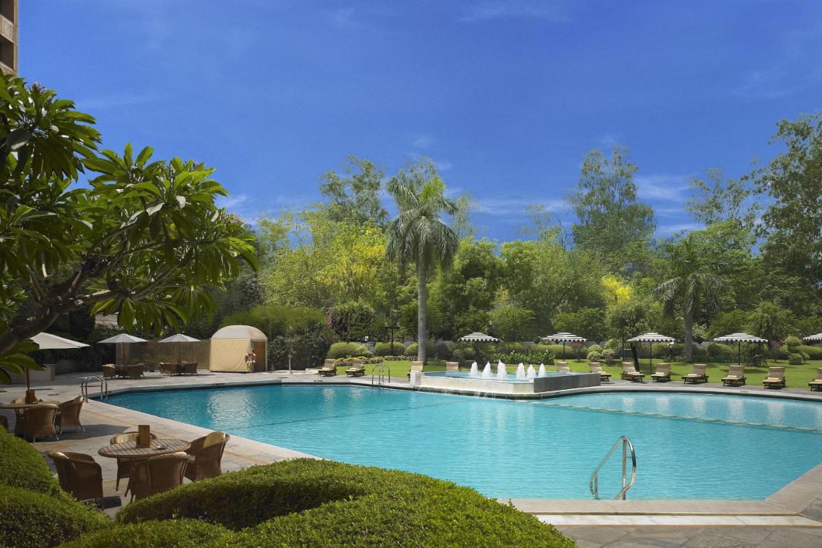 a large swimming pool with chairs and umbrellas at ITC Maurya, a Luxury Collection Hotel, New Delhi in New Delhi a large swimming pool with chairs and umbrellas at ITC Maurya, a Luxury Collection Hotel, New Delhi in New Delhi