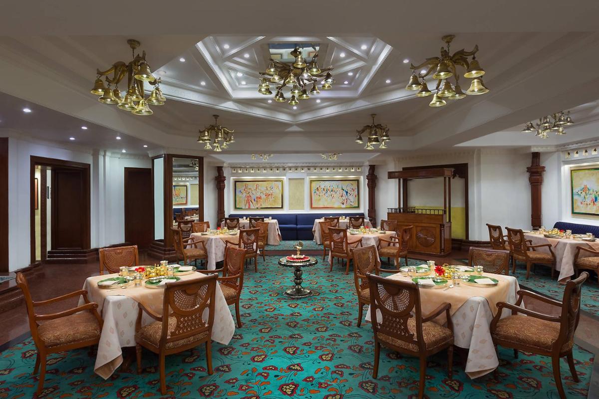 a dining room with tables and chairs and chandeliers at ITC Kakatiya, a Luxury Collection Hotel, Hyderabad in Hyderabad