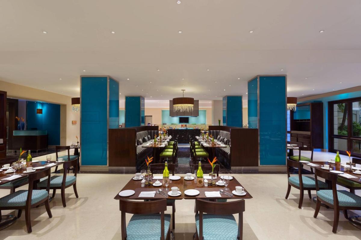 a restaurant with tables and chairs and a bar at ITC Kakatiya, a Luxury Collection Hotel, Hyderabad in Hyderabad