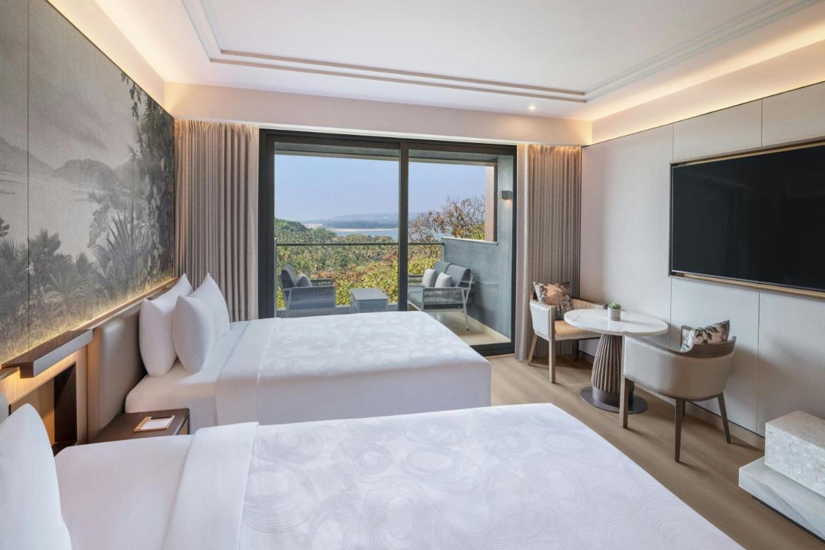 a hotel room with two beds and a flat screen tv at JW Marriott Goa in Vagator a hotel room with two beds and a flat screen tv at JW Marriott Goa in Vagator