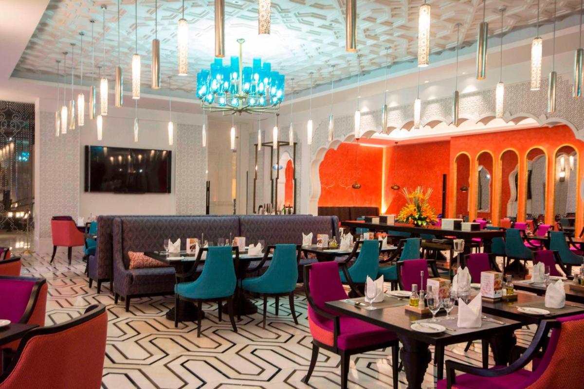 a dining room with tables and chairs and a chandelier at ITC Rajputana, a Luxury Collection Hotel, Jaipur in Jaipur