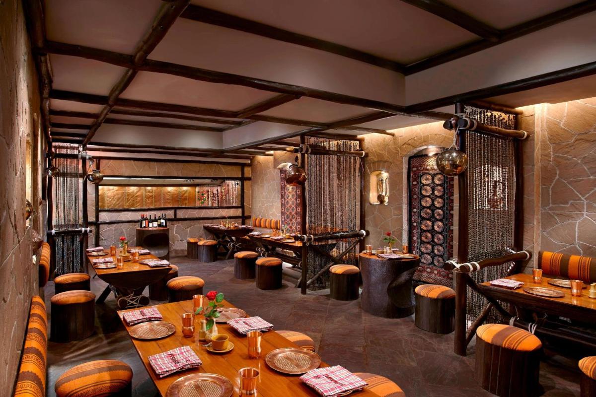 a restaurant with wooden tables and chairs in a room at ITC Rajputana, a Luxury Collection Hotel, Jaipur in Jaipur