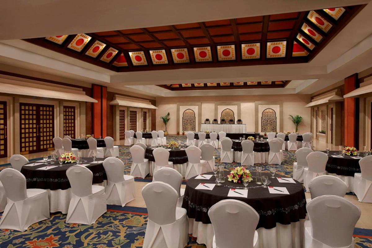 a ballroom with tables and white chairs and a ballroom with tables and white at ITC Rajputana, a Luxury Collection Hotel, Jaipur in Jaipur +20 photos