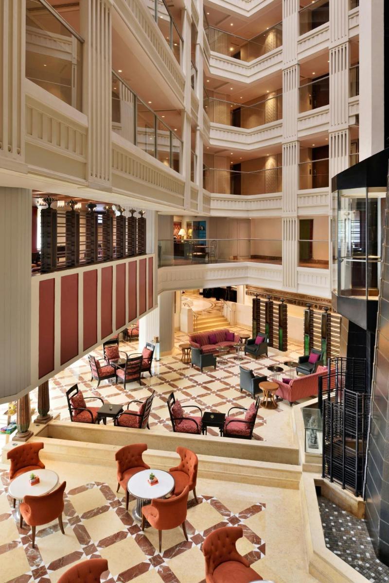 a large lobby with tables and chairs in a building at Hyderabad Marriott Hotel & Convention Centre in Hyderabad