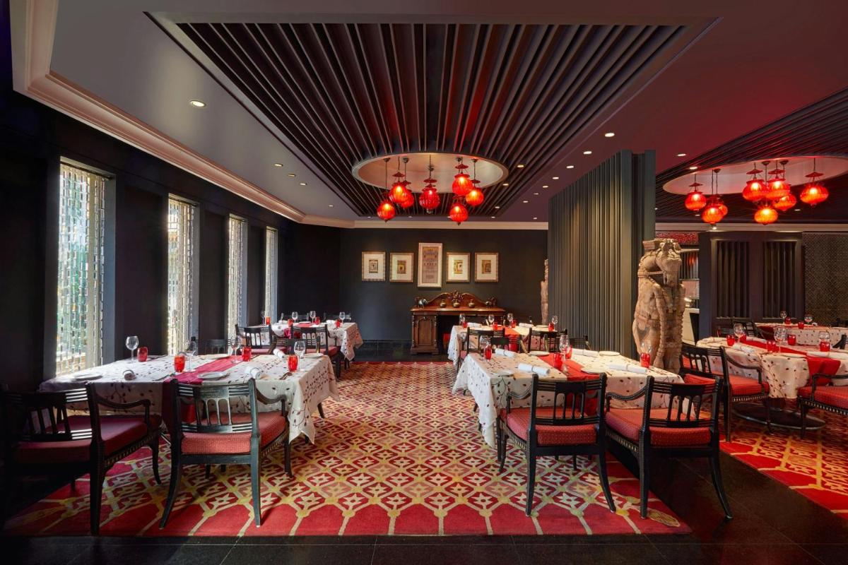 a dining room with tables and chairs and a piano at Hyderabad Marriott Hotel & Convention Centre in Hyderabad