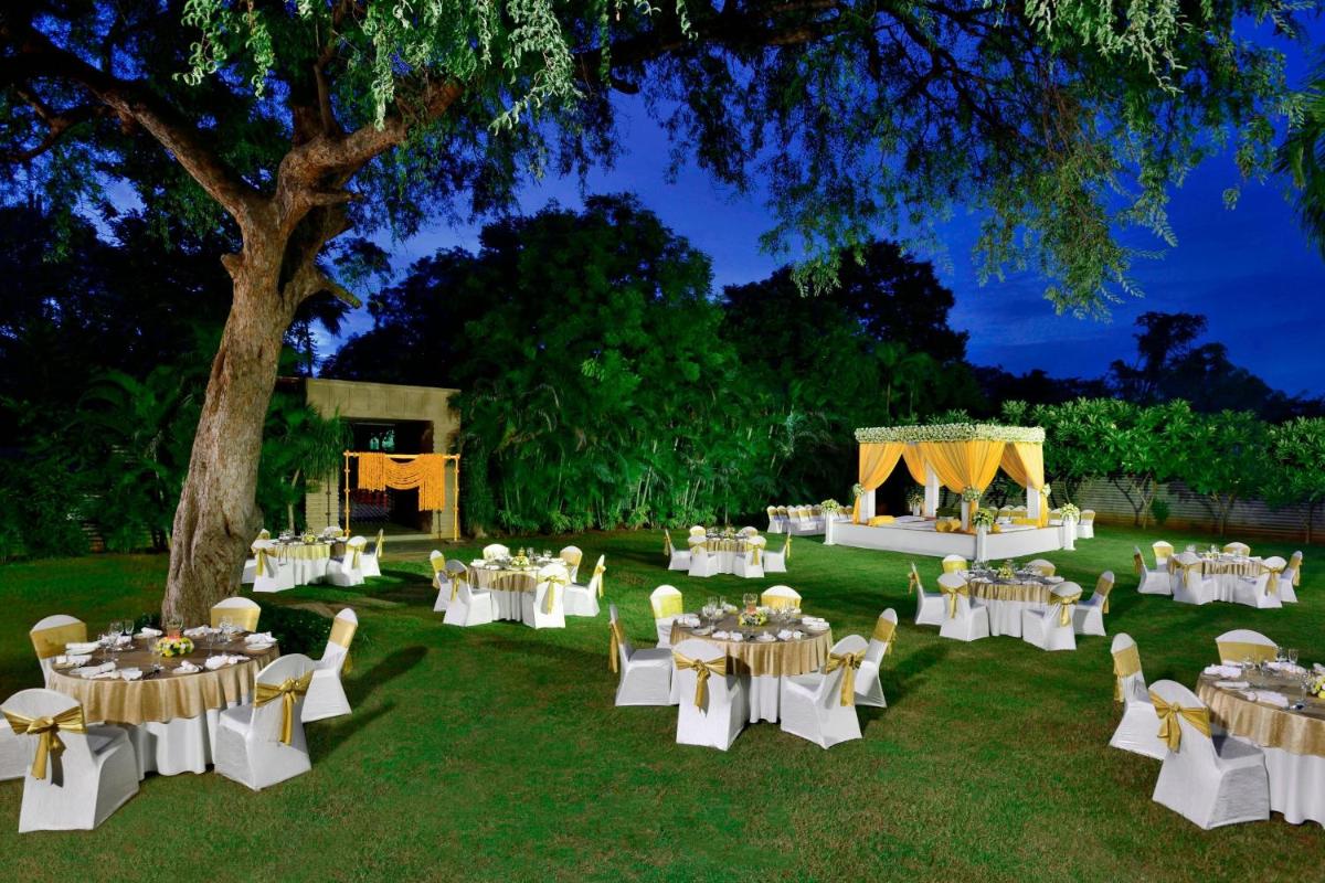 a garden with white tables and chairs and a stage at Hyderabad Marriott Hotel & Convention Centre in Hyderabad +112 photos