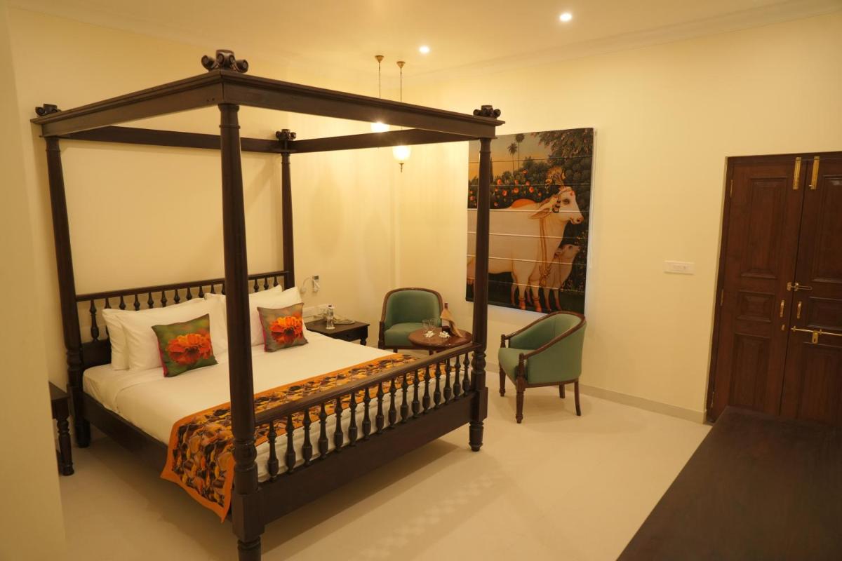 a bedroom with a canopy bed and a chair at The Grand Imperial - Heritage Hotel in Agra