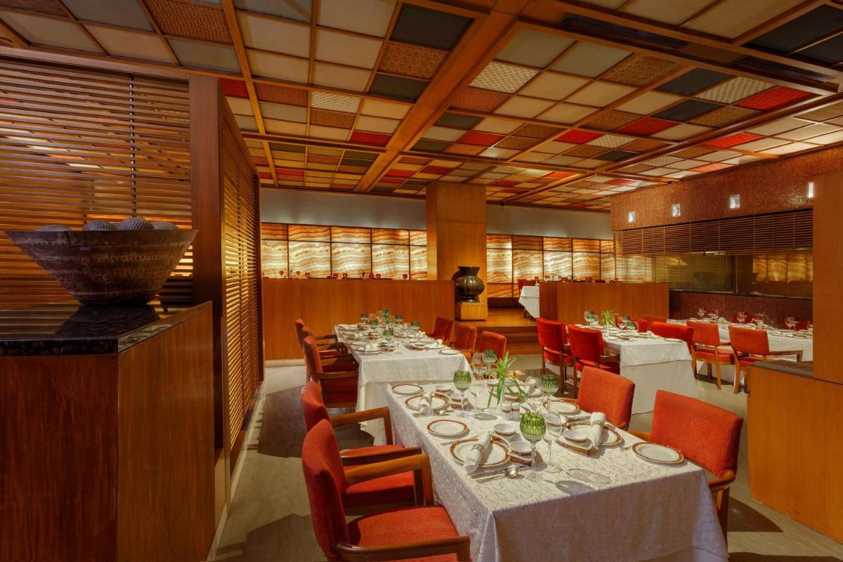 a dining room with white tables and red chairs at ITC Sonar, a Luxury Collection Hotel, Kolkata in Kolkata