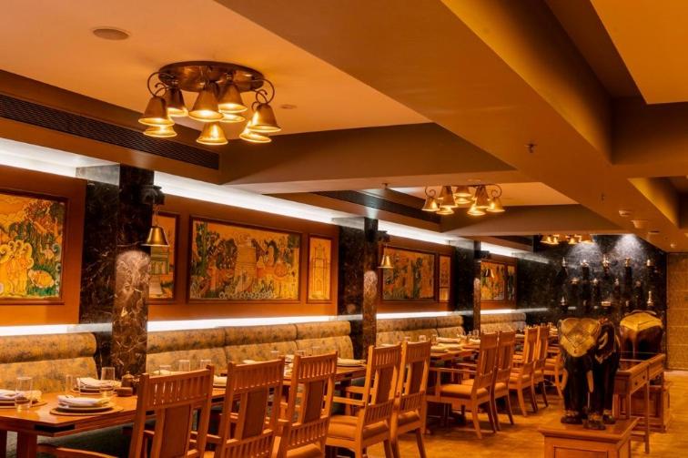 a dining room with tables and chairs and paintings at Vivanta Thiruvananthapuram in Trivandrum