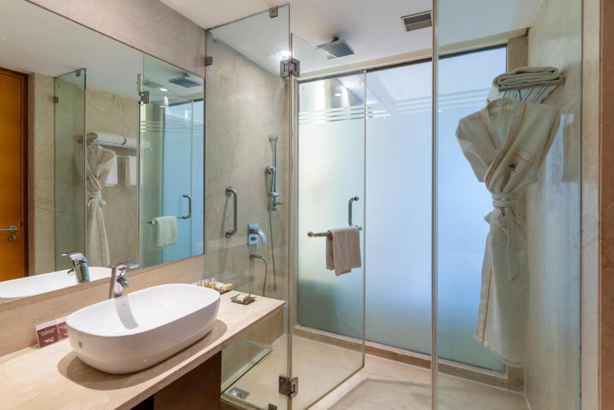 a bathroom with a sink and a glass shower at Pride Plaza Hotel, Kolkata in Kolkata