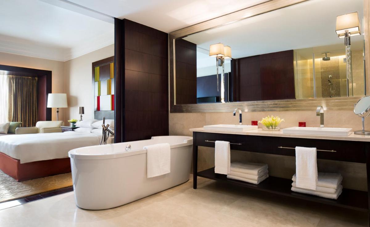 a bathroom with a tub and two sinks and a bed at JW Marriott Hotel Bengaluru in Bengaluru
