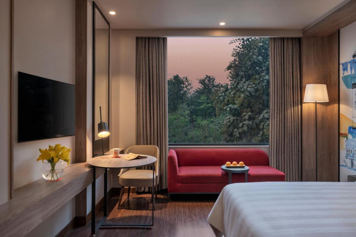 a hotel room with a red chair and a window at Welcomhotel by ITC Hotels, Delhi-Gurugram Highway in New Delhi