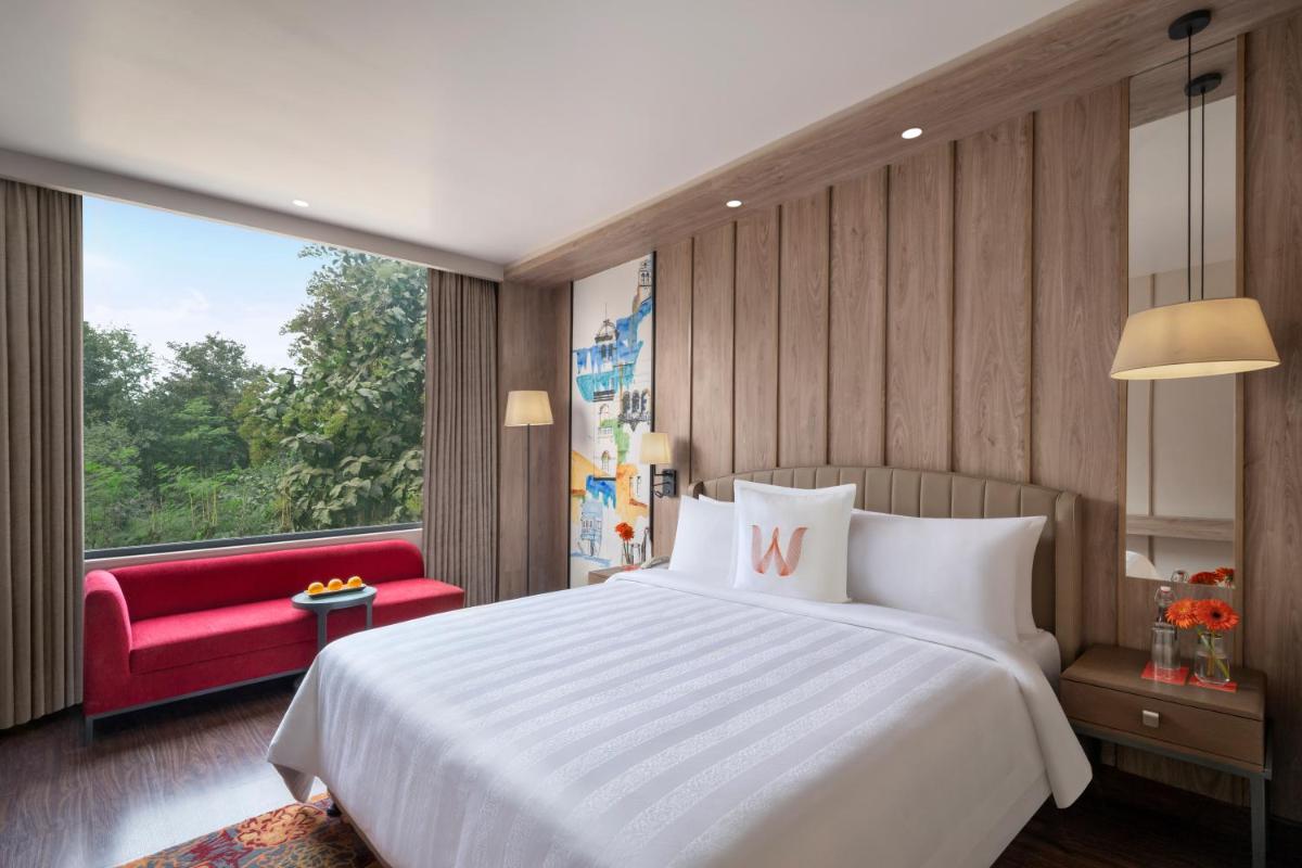 a bedroom with a large white bed and a red couch at Welcomhotel by ITC Hotels, Delhi-Gurugram Highway in New Delhi