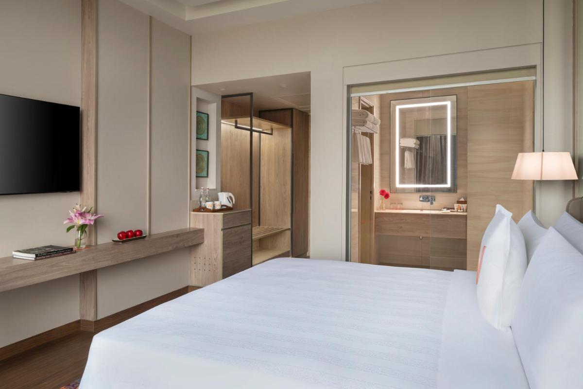 a bedroom with a large white bed and a bathroom at Welcomhotel by ITC Hotels, Delhi-Gurugram Highway in New Delhi