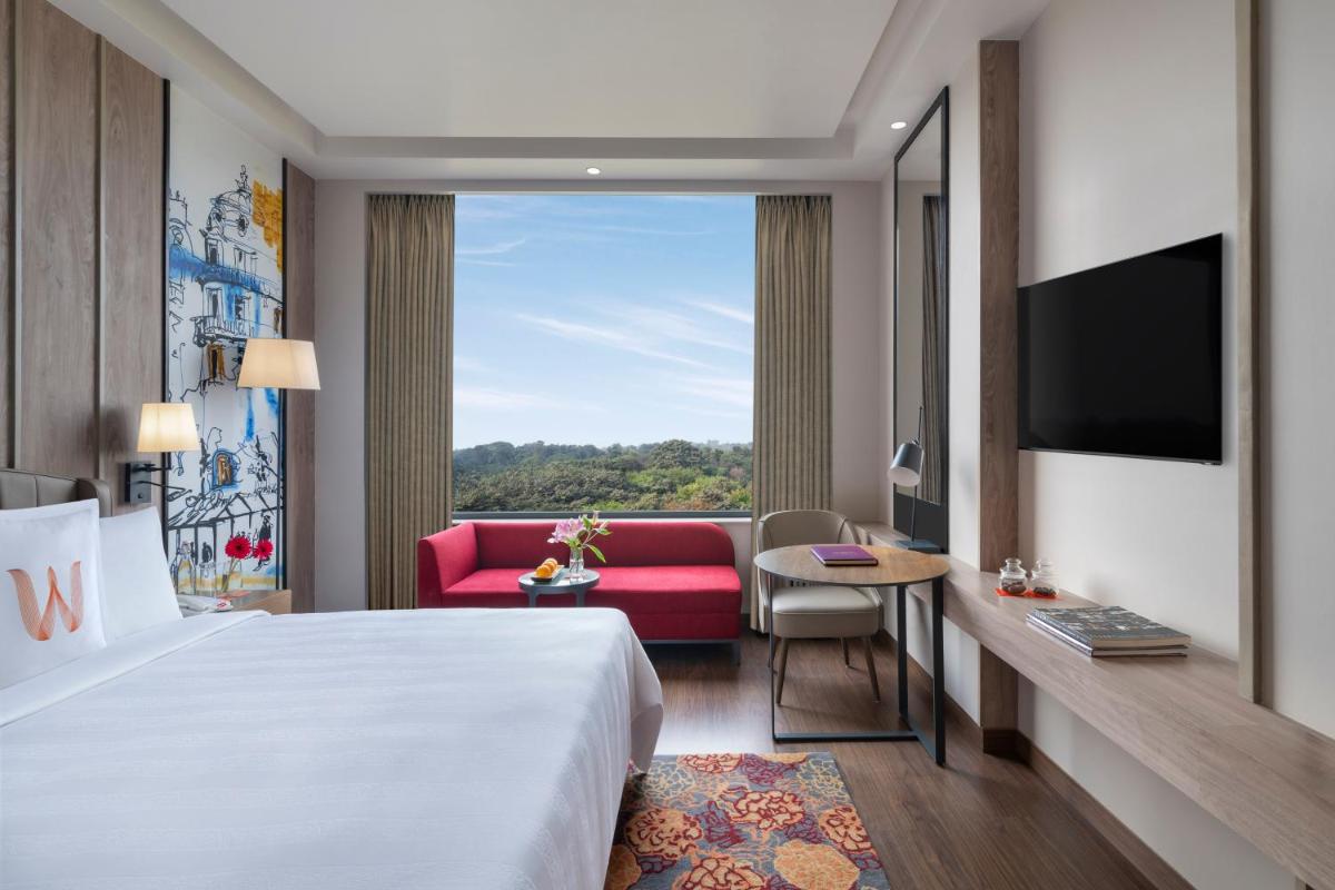 a hotel room with a large bed and a red couch at Welcomhotel by ITC Hotels, Delhi-Gurugram Highway in New Delhi a hotel room with a large bed and a red couch at Welcomhotel by ITC Hotels, Delhi-Gurugram Highway in New Delhi