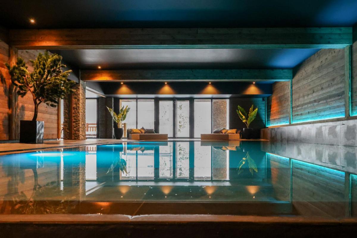 une piscine dans une maison avec des lumières allumées dans l'établissement Domaine de Montagne - Hôtel Chalet Frère Joseph, à Ventron