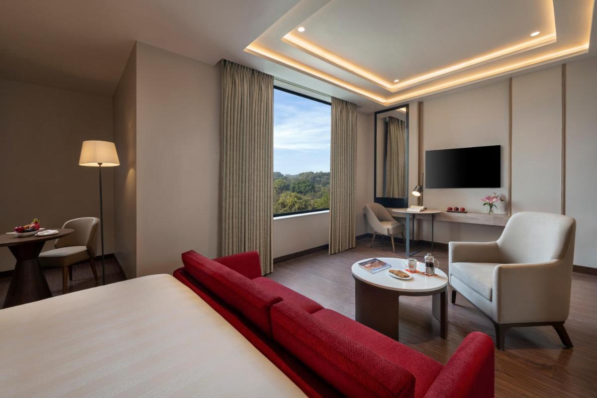 a hotel room with a red couch and a large window at Welcomhotel by ITC Hotels, Delhi-Gurugram Highway in New Delhi