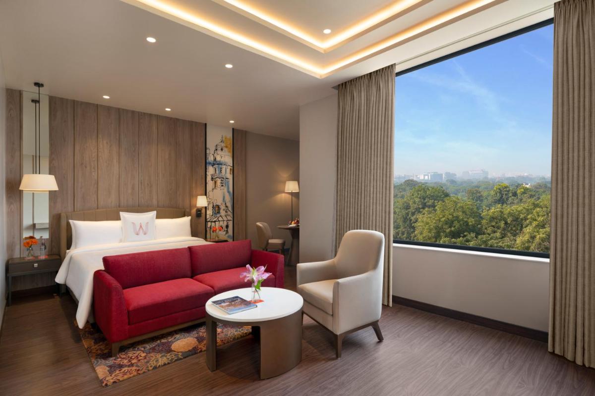 a hotel room with a red couch and a large window at Welcomhotel by ITC Hotels, Delhi-Gurugram Highway in New Delhi