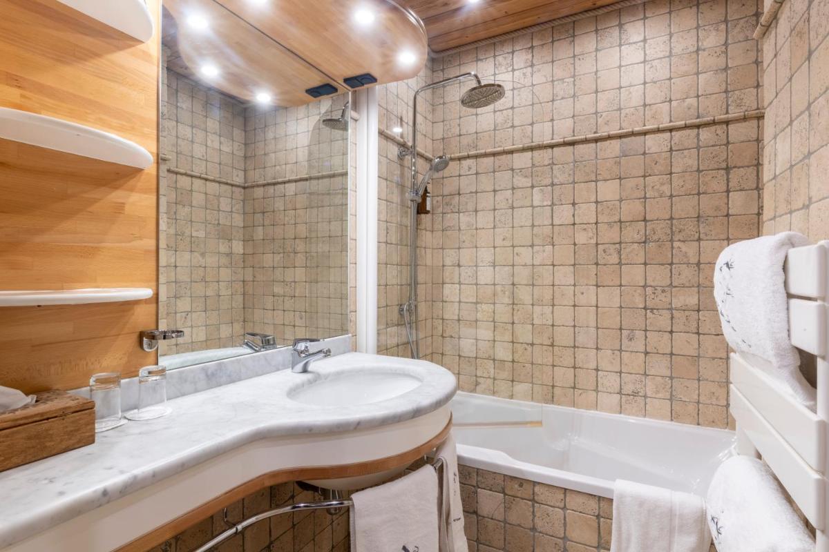 une salle de bains avec lavabo et baignoire dans l'établissement Hôtel Macchi Restaurant & Spa, à Châtel