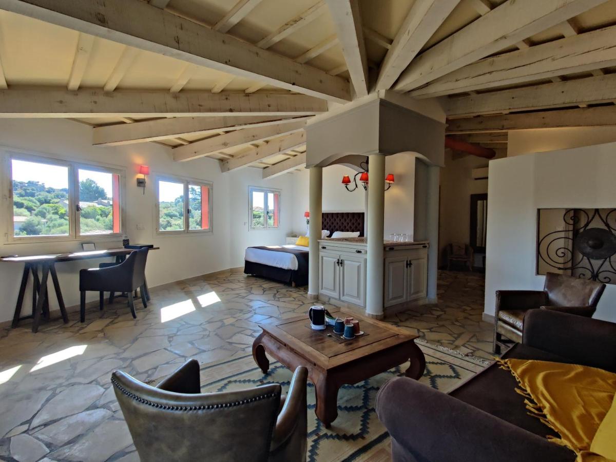 un salon avec un lit, une table et des chaises dans l'établissement Le Roc E Fiori Hotel - Teritoria, à Porto-Vecchio