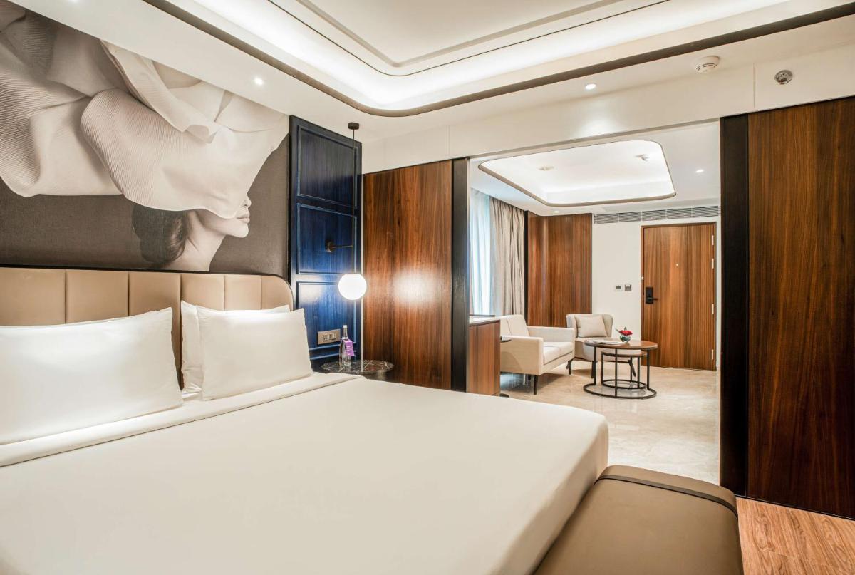a bedroom with a bed and a living room at Radisson Blu Hotel Ahmedabad in Ahmedabad