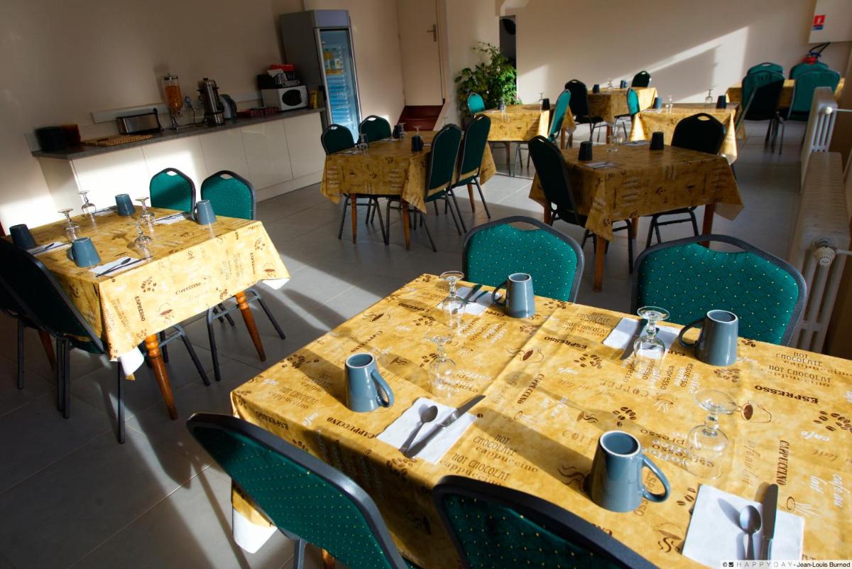 une salle à manger avec des tables en bois et des chaises vertes dans l'établissement Hôtel La Tente Verte, à Loon-Plage