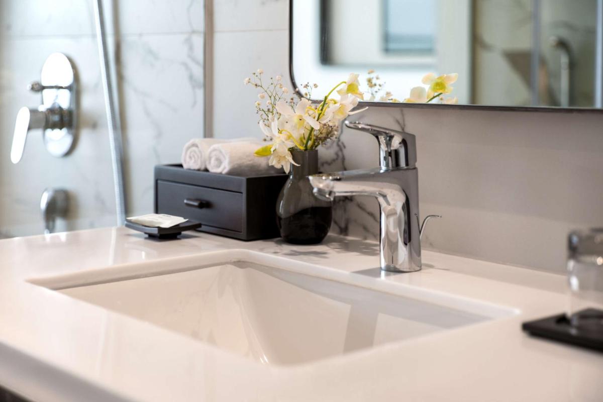 a bathroom sink with a mirror and a vase of flowers at Radisson Blu Bengaluru Outer Ring Road in Bengaluru