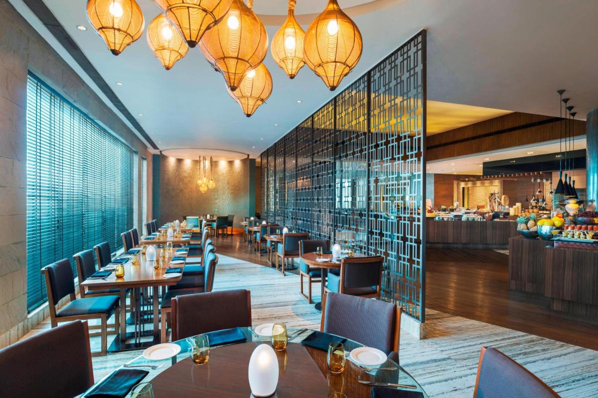 a dining room with tables and chairs and chandeliers at The St. Regis Mumbai in Mumbai