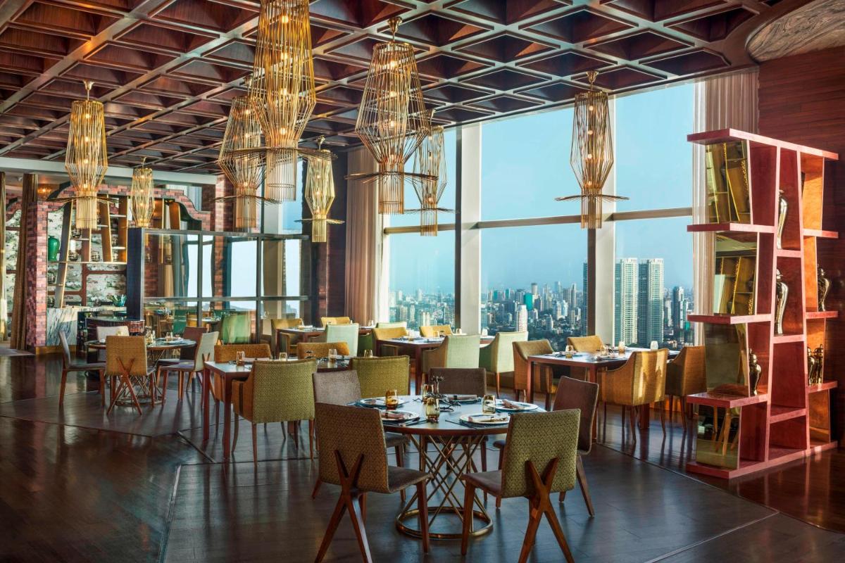 a restaurant with tables and chairs and a view of the city at The St. Regis Mumbai in Mumbai
