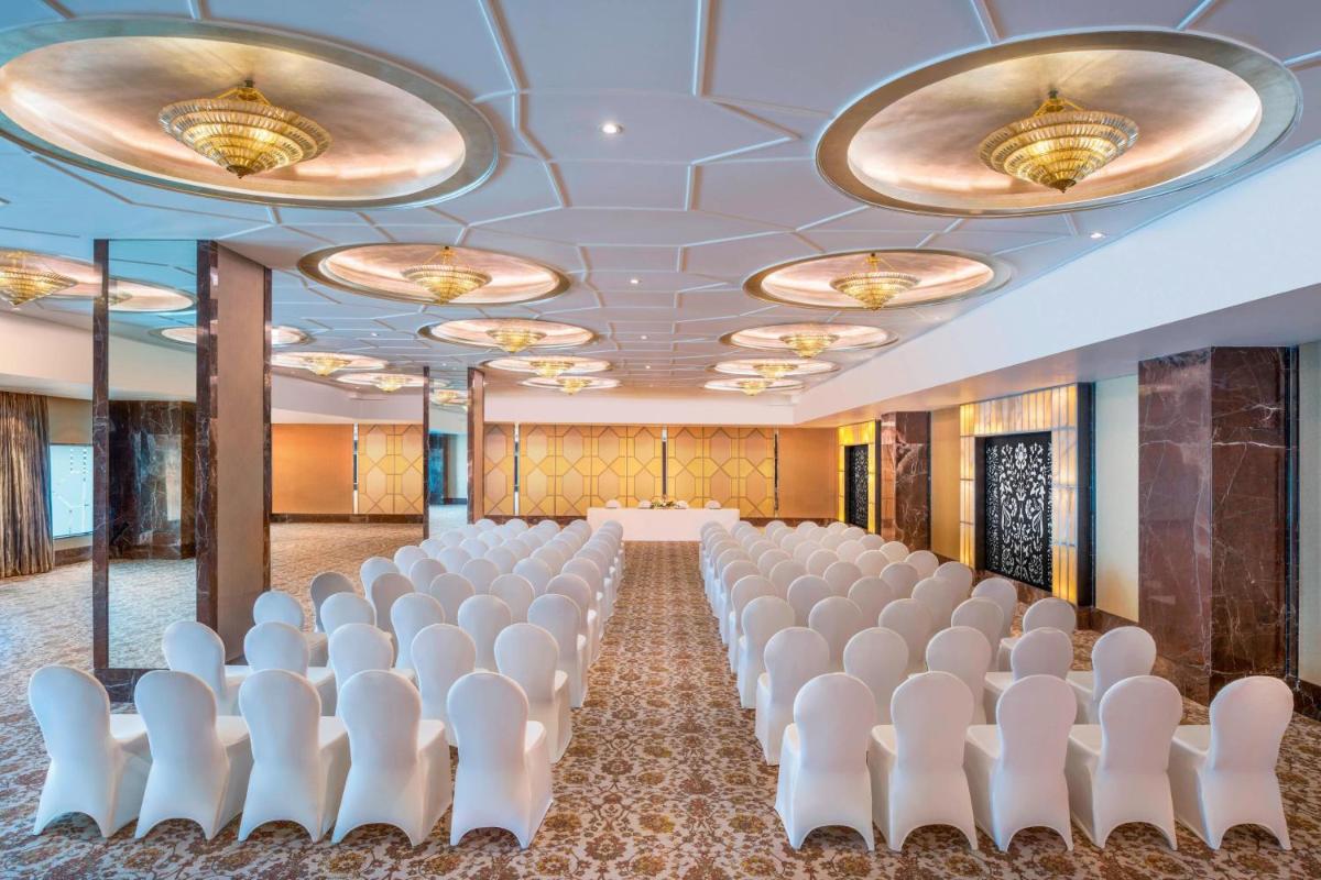 a conference room with rows of white chairs and a stage at The St. Regis Mumbai in Mumbai