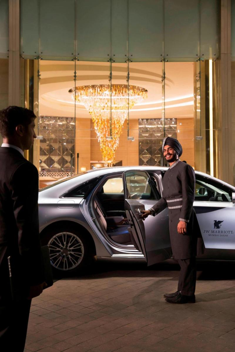 a man is standing in front of a car at JW Marriott Mumbai Sahar Airport in Mumbai a man is standing in front of a car at JW Marriott Mumbai Sahar Airport in Mumbai