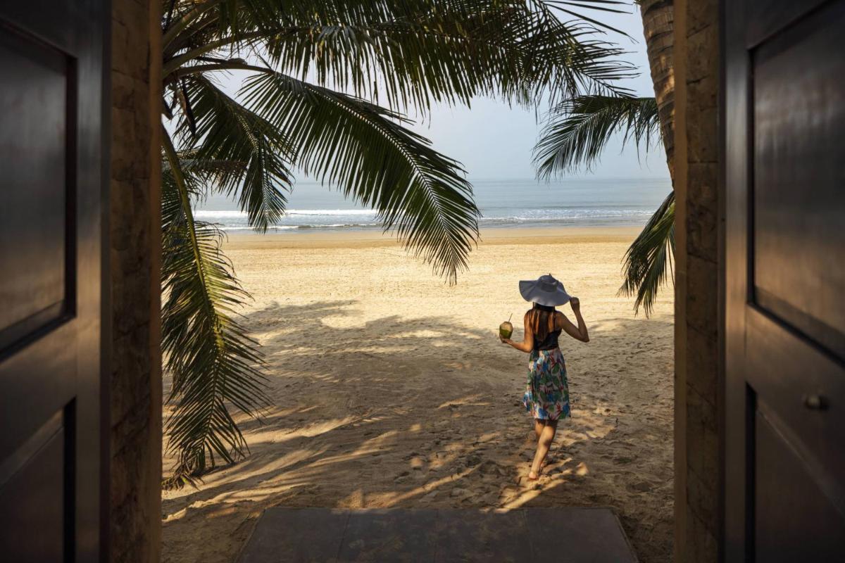 a woman with a hat walking on the beach at JW Marriott Mumbai Juhu in Mumbai