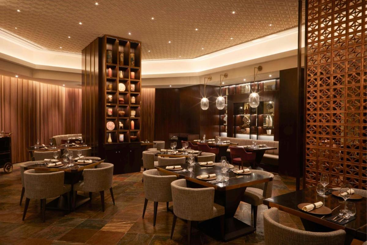 a restaurant with tables and chairs and wine bottles at JW Marriott Mumbai Juhu in Mumbai