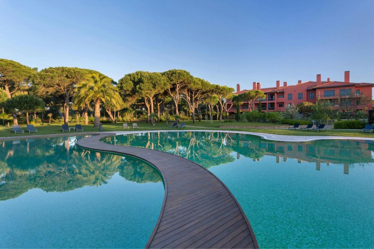 uma piscina com um caminho de madeira em um parque em Sheraton Cascais Resort - Hotel & Residences em Cascais