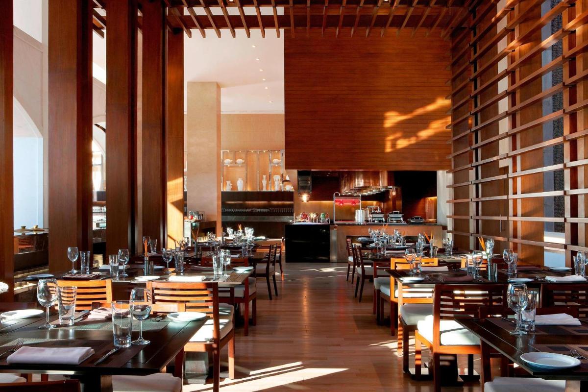 a restaurant with tables and chairs in a room at The Westin Hyderabad Mindspace in Hyderabad