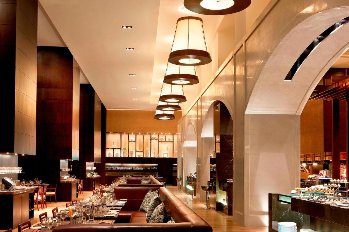 a restaurant with a long bar with tables and chairs at The Westin Hyderabad Mindspace in Hyderabad