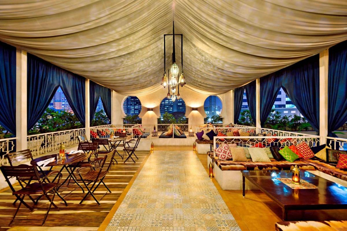 a large room with tables and couches and a curtain at The Westin Hyderabad Mindspace in Hyderabad