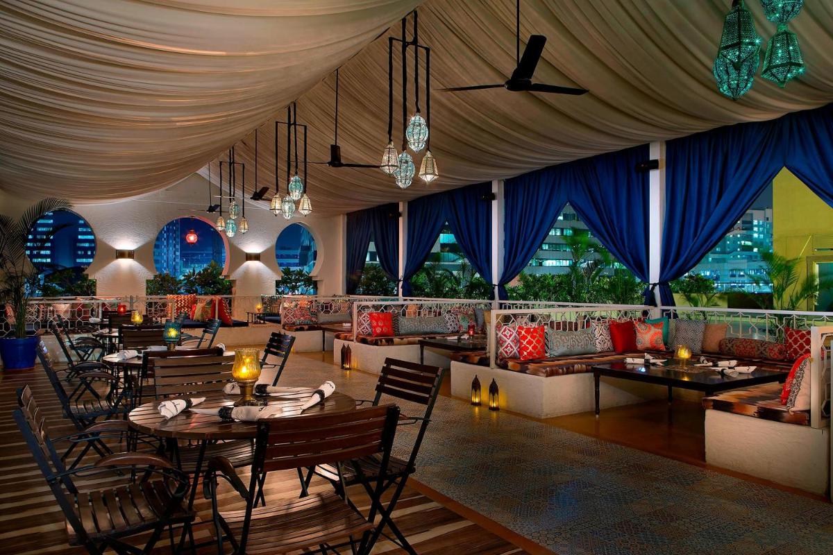 a restaurant with tables and chairs and blue curtains at The Westin Hyderabad Mindspace in Hyderabad