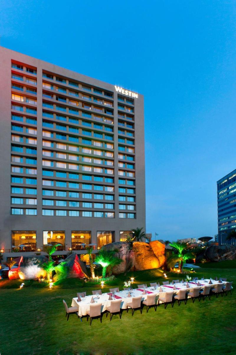 a hotel with tables and chairs in front of a building at The Westin Hyderabad Mindspace in Hyderabad