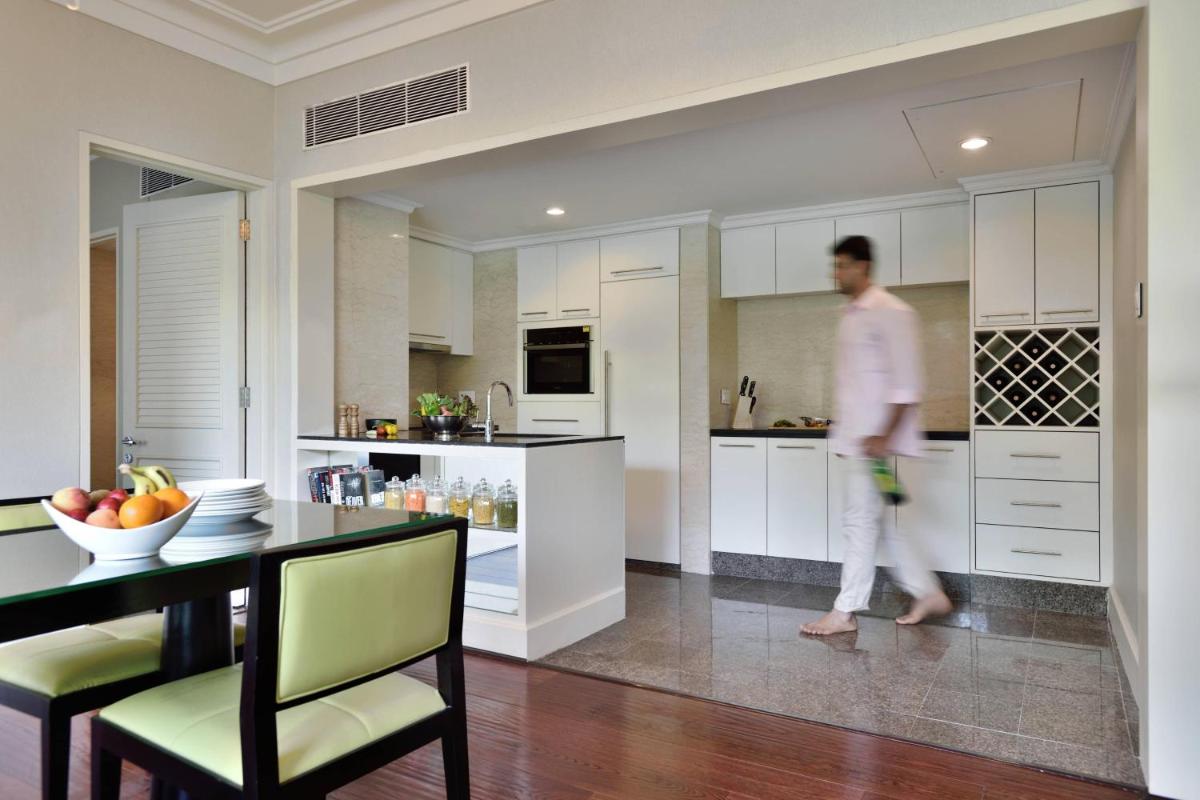 a man is walking in a kitchen with a table at Marriott Executive Apartment - Lakeside Chalet, Mumbai in Mumbai
