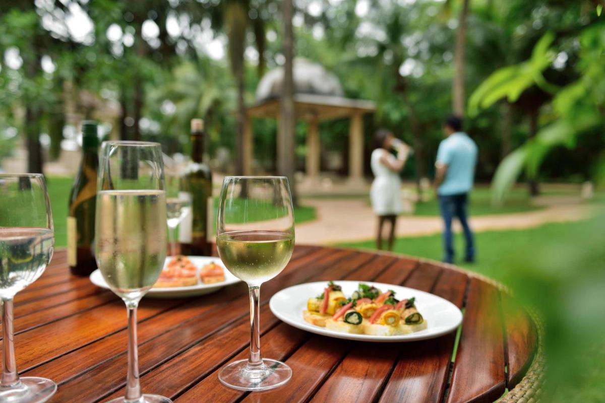 two glasses of wine and a plate of food on a wooden table at Marriott Executive Apartment - Lakeside Chalet, Mumbai in Mumbai