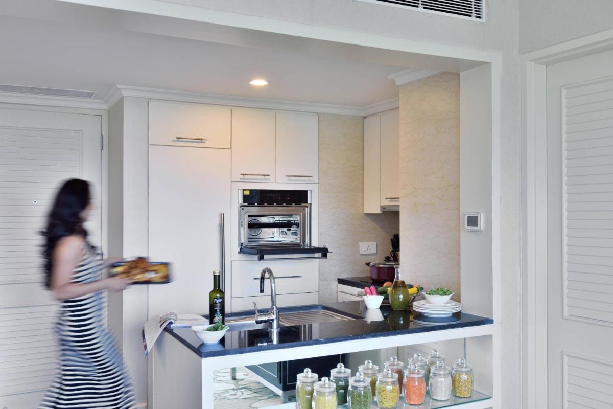 a woman walking in a kitchen with a sink at Marriott Executive Apartment - Lakeside Chalet, Mumbai in Mumbai
