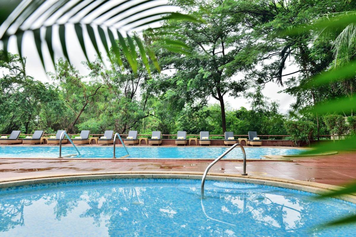 a swimming pool with lounge chairs in a garden at Marriott Executive Apartment - Lakeside Chalet, Mumbai in Mumbai a swimming pool with lounge chairs in a garden at Marriott Executive Apartment - Lakeside Chalet, Mumbai in Mumbai