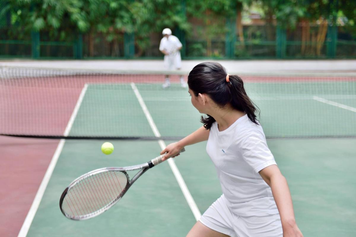 a young girl hitting a tennis ball with a racket at Marriott Executive Apartment - Lakeside Chalet, Mumbai in Mumbai