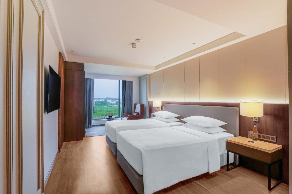 a bedroom with a large white bed and a window at Hyatt Place Haridwar in Haridwār