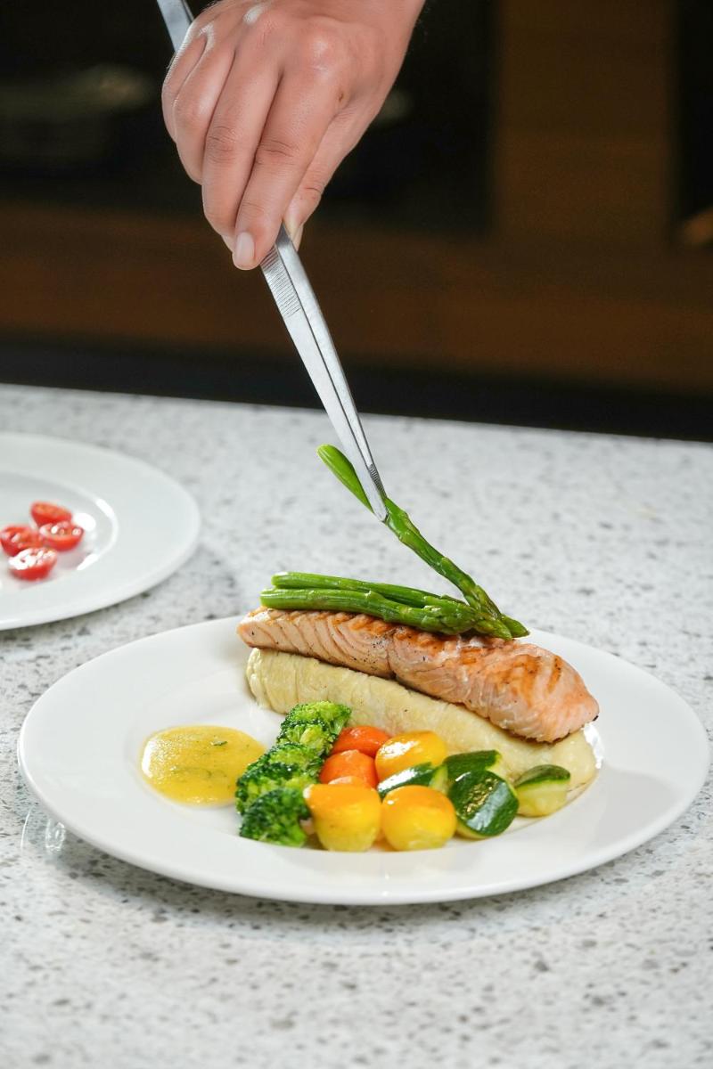 a person holding a fork and knife over a plate of food at Hyatt Place Haridwar in Haridwār