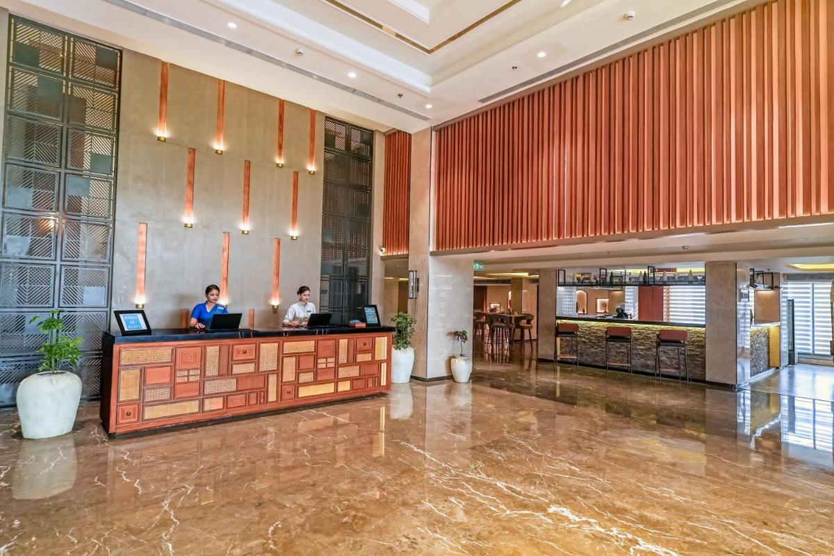 a lobby of a hotel with two people sitting at a counter at Hyatt Place Haridwar in Haridwār
