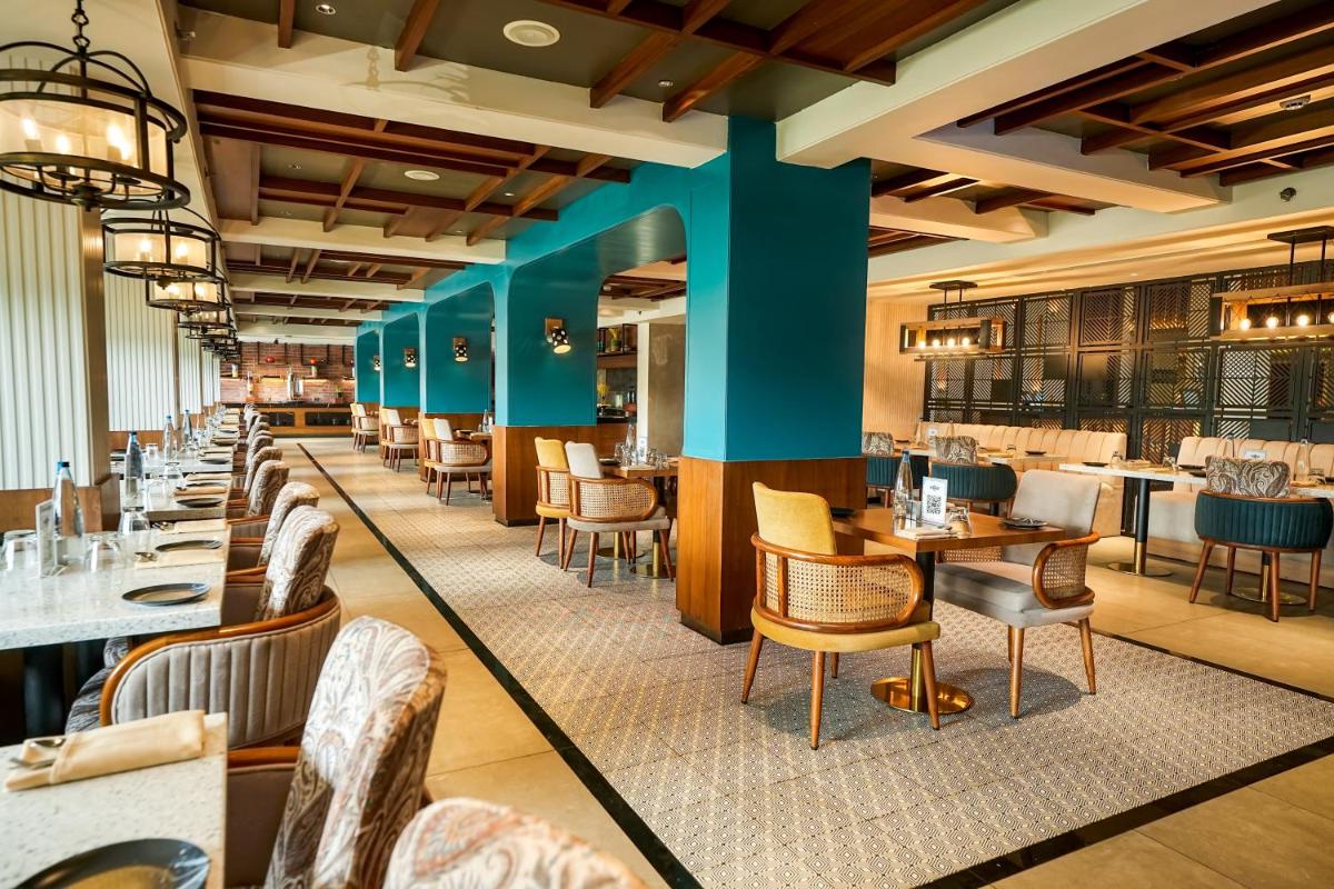 a restaurant with a long line of tables and chairs at Hyatt Place Haridwar in Haridwār