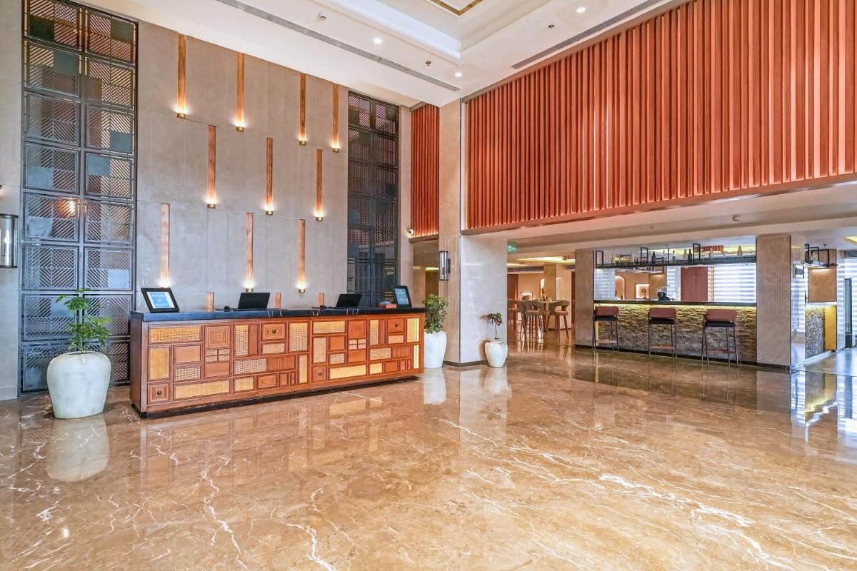 a lobby with a reception desk in a building at Hyatt Place Haridwar in Haridwār