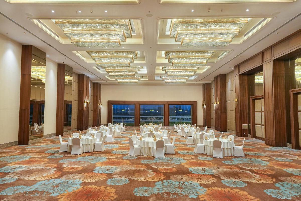 a large room with white tables and chairs in it at Hyatt Place Haridwar in Haridwār